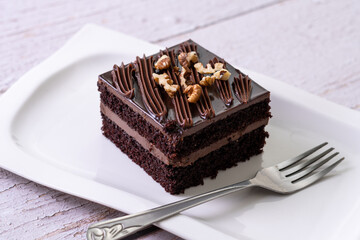 chocolate cakes pastries brownies on white ceramic plate with nuts topping  on a white wooden rustic desk table