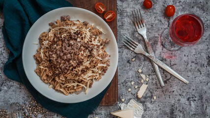 Baked Fusilli topped with minced meat and torched cheese on a grey concrete background