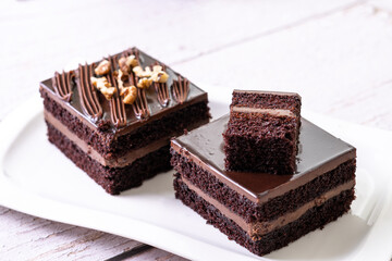 chocolate cakes pastries brownies on white ceramic plate with nuts topping  on a white wooden rustic desk table