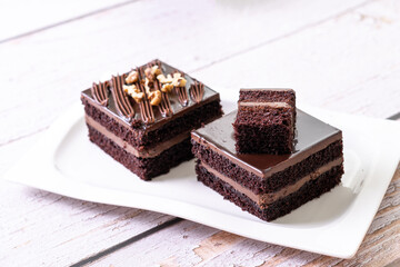 chocolate cakes pastries brownies on white ceramic plate with nuts topping  on a white wooden rustic desk table