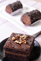 chocolate cakes pastries brownies on white ceramic plate with nuts topping  on a white wooden rustic desk table