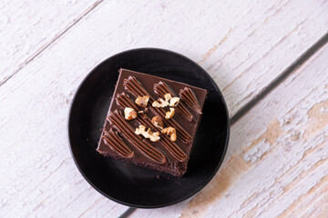 chocolate cakes brownies pastries dessert on black ceramic plate with nuts topping