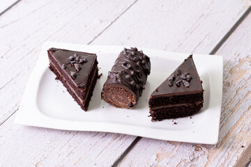 chocolate cakes pastries brownies on white ceramic plate with nuts topping  on a white wooden rustic desk table