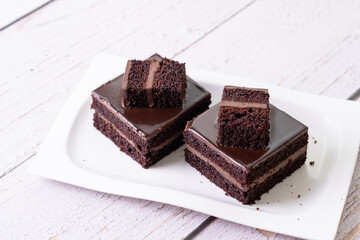 chocolate cakes pastries brownies on white ceramic plate with nuts topping  on a white wooden rustic desk table