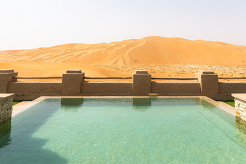 Luxurious pool facing the sand dunes in desert; luxury hotel travel destination concept