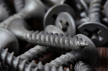 Metal screws close-up on a wooden background. Tools for fixing and repairing. Macrophotography.