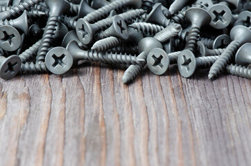 Metal screws on a wooden background. Tool for fixing and repairing. Copy space