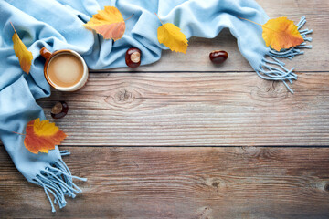 Autumn leaves, cup of coffee and warm scarf on wooden table. Fall season, leisure time, Sunday relaxing, coffee break and still life concept. Selective focus. Top view, copy space.
