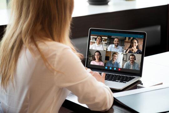 Back View Of Female Employee Talk Speak On Video Call On Laptop With Diverse Businesspeople. Businesswoman Have Webcam Digital Virtual Meeting Briefing Online On Computer With Colleagues In Office.