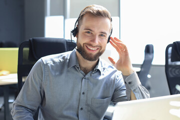 Smiling friendly handsome young male call centre operator. - obrazy, fototapety, plakaty