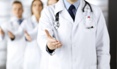 Team of unknown doctors is offering helping hand to the patients, close up. Physicians ready to help people. Medical help, insurance in health care, medicine concept