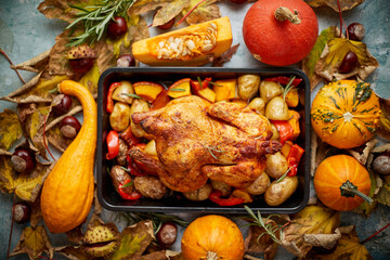 Roasted chicken or turkey garnished with pumpkins, pepper and potatoes. Served on a rustic table