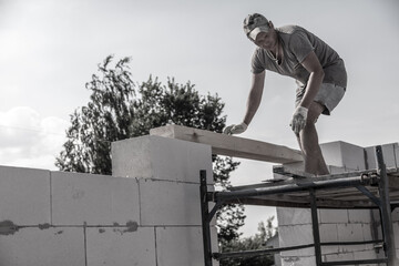 A worker builds the walls of a house from aerated concrete bricks.