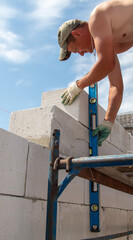 A worker builds the walls of a house from aerated concrete bricks.