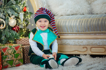 A little boy with Down syndrome in a New Year's gnome costume near the Christmas tree.
