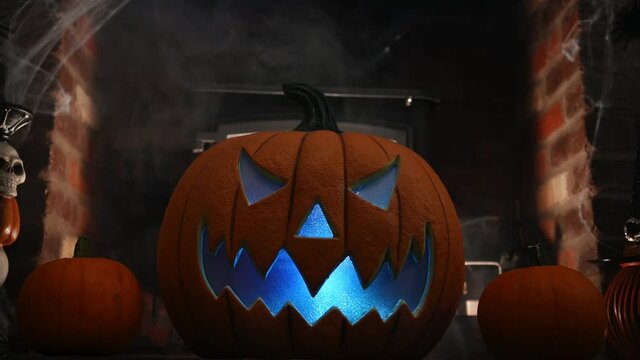 4k video of pumpking changing colours on spooky fire place. wram flickering backlight from fire. smoke behind pumpkin