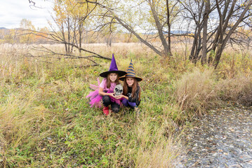 Girlfriends in a witch costume. Children cast magic over skull.