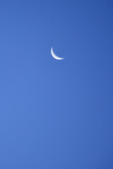 Obraz na płótnie Canvas An old moon in the blue morning sky.