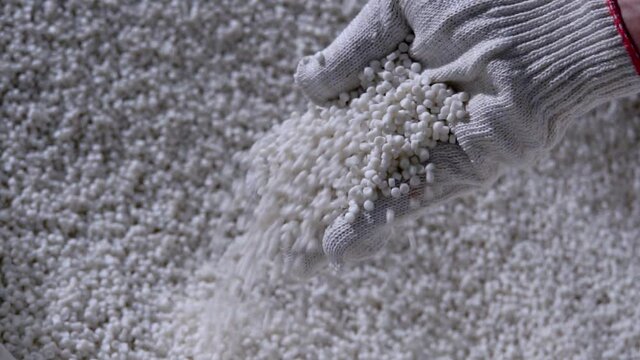 Plastic granules are poured from the hand in glow. Plastic granules, dye, polymer granules are used for the production of plastic products