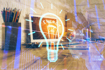 Computer on desktop in office with bulb icon hologram. Double exposure. Concept of idea.