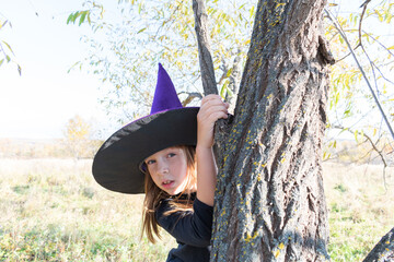 Girl in a witch costume looks out.