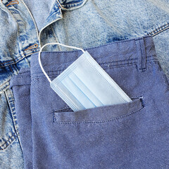 A medical protective mask in blue shorts pocket. Accessories in the modern world. The biological...