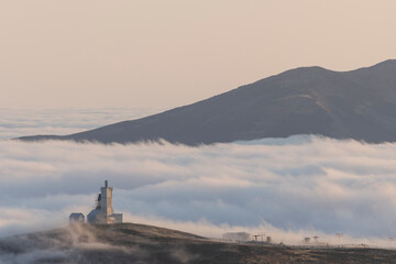 Amazing and cloudy sunrise in the mountains. Ski lift surrounded by clouds.