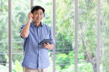 senior asian man wearing headphones and enjoy favorite music from tablet