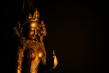 Close up of isolated illuminated hindu Shiva god golden bronze statue with raised hand on blank...