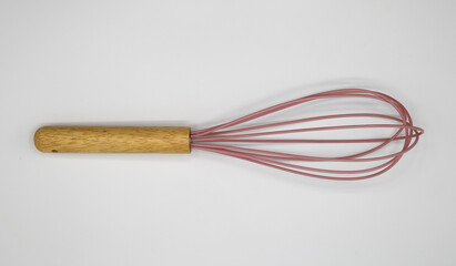 Top down view on one isolated whisk with wood handle and pink wire loops on blank white background