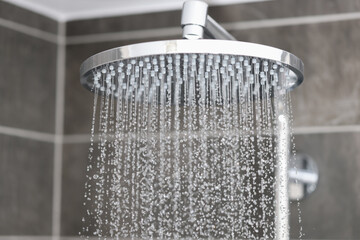 Close-up of water streaming from rain shower head in bathroom. Sale of plumbing concept.