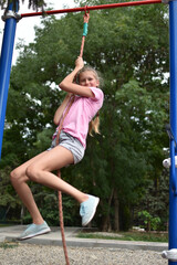 Caucasian gymnast teenager girl on outdoor playground. children's sports for health.