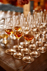 Glasses with brandy or cognac stand in a row. Blurred background, warm tinted. Tasting glasses with aged french cognac brandy