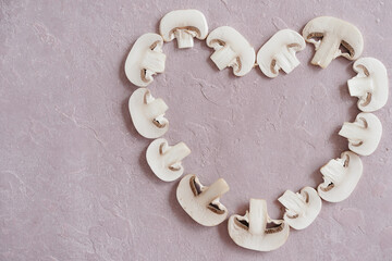 slices of champignons in shape of heart on pink background. High quality photo