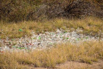 Secret dump of plastic bottles close up - pollution of the earth, violation of ecology