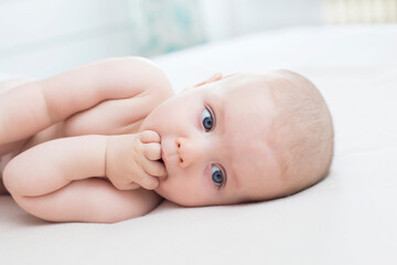 Little baby girl lying with hand in mouth