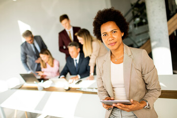 African American businesswoman standing and using digital tablet in a modern office