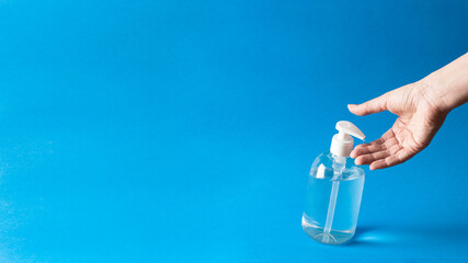 Naklejka premium Anti bacterial gel poured on hand on blue background.Large image with copy space