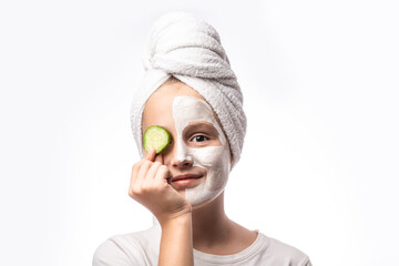 Spa teen girl applying facial clay mask and cucumbers on eyes isolated on white background. Healthy beauty clean treatment and cosmetology products concept