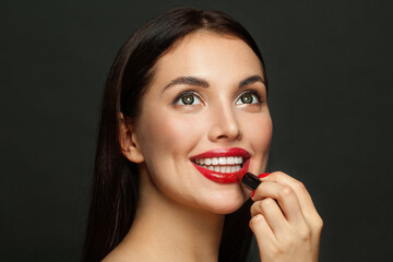 Attractive woman face with red lips and lipstick close up on black background