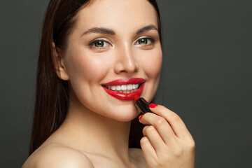 Pretty woman face with red glossy lips and lipstick on black background