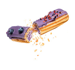 Delicious eclair with blueberries broken into two halves in the air close-up on a white background
