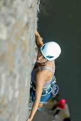 fitness, extreme sport and healthy lifestyle concept - Climber overcomes challenging climbing route. A girl climbs a rock. Woman engaged in extreme sport. Extreme hobby.