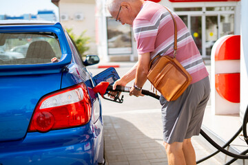 old senior man refill his car with gasoline on the fuel station, tourist traveling