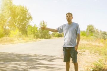 lonely man standing on the roadside hitch-hiking, thumb up gesture waiting for the car, tourist...