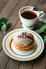 Coffee glazed donut with tea on the wooden table