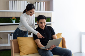 Young asian woman and man pointing at laptop Computer at home