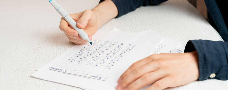 close up person's hands writing answers in the social test on a paper sheet