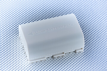 Weisse Lithium-Batterie (Li-ion Battery / Akku) liegt in einem kühlen technischen Licht auf einem...