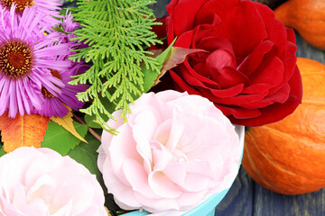 Modern bouquet of colorful flowers. Red and pink roses. Purple aster. Ripe pumpkin. Green branch of juniper